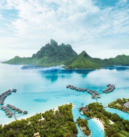 Aerial view of Bora Bora showcasing turquoise waters, lush green mountains, and overwater bungalows. The scene conveys tranquility and tropical paradise.